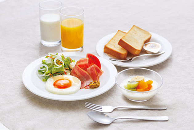 洋食の朝食セット、目玉焼きとサラダ、ベーコン、トースト、フルーツ、牛乳とオレンジジュース。