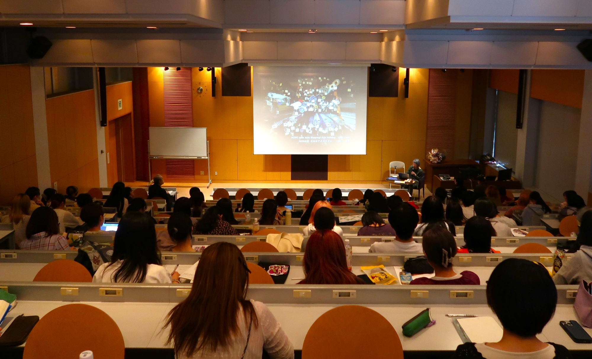 特別講義の会場風景。180名収容ホールはほぼ満席。会場のスクリーンに須藤先生の作品が投影されている。