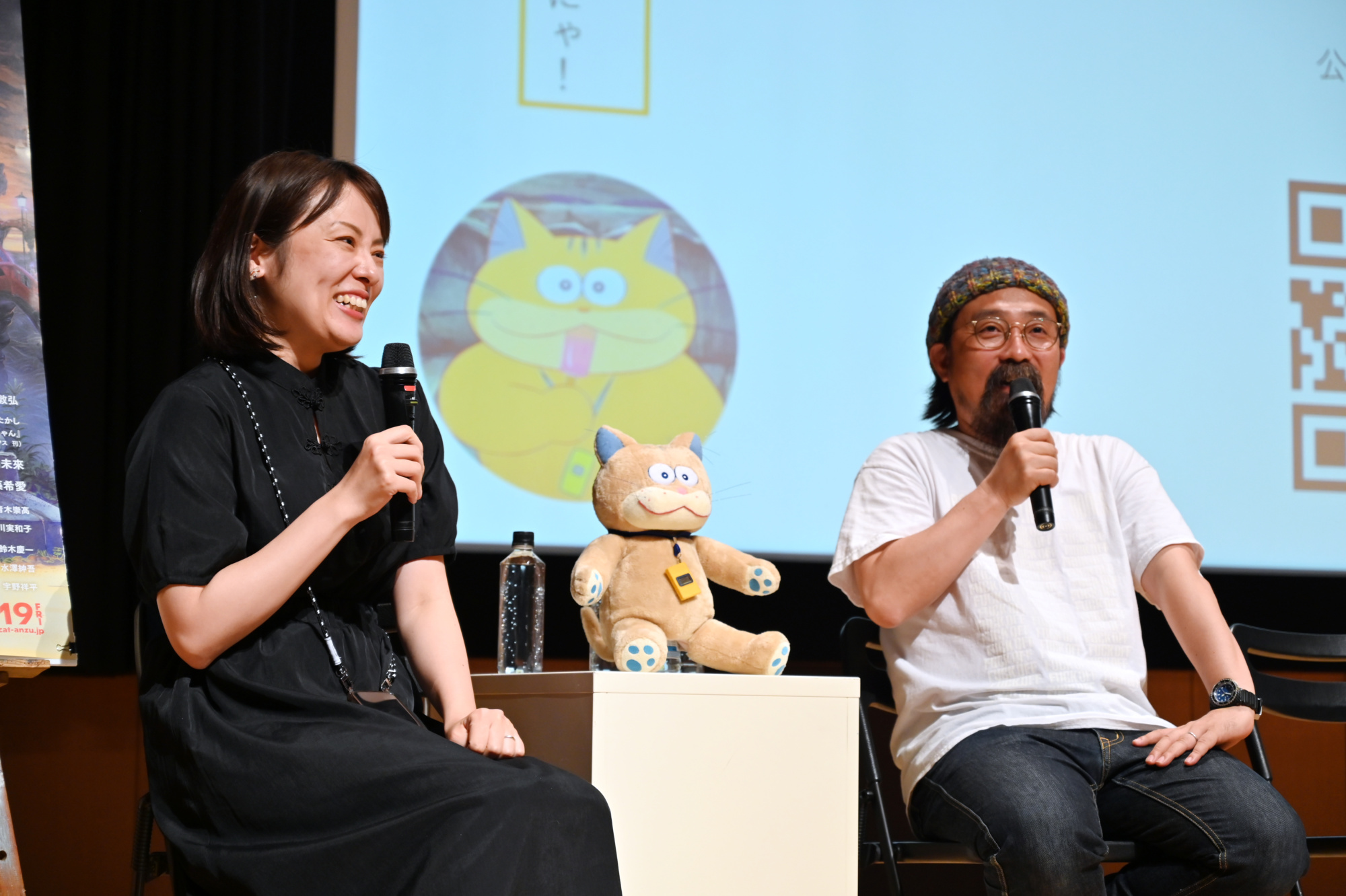 ステージ上の左側久野遥子監督、右側山下敦弘監督がアニメキャラクターあんずちゃんのぬいぐるみと共に笑顔で学生たちに映画について買っている