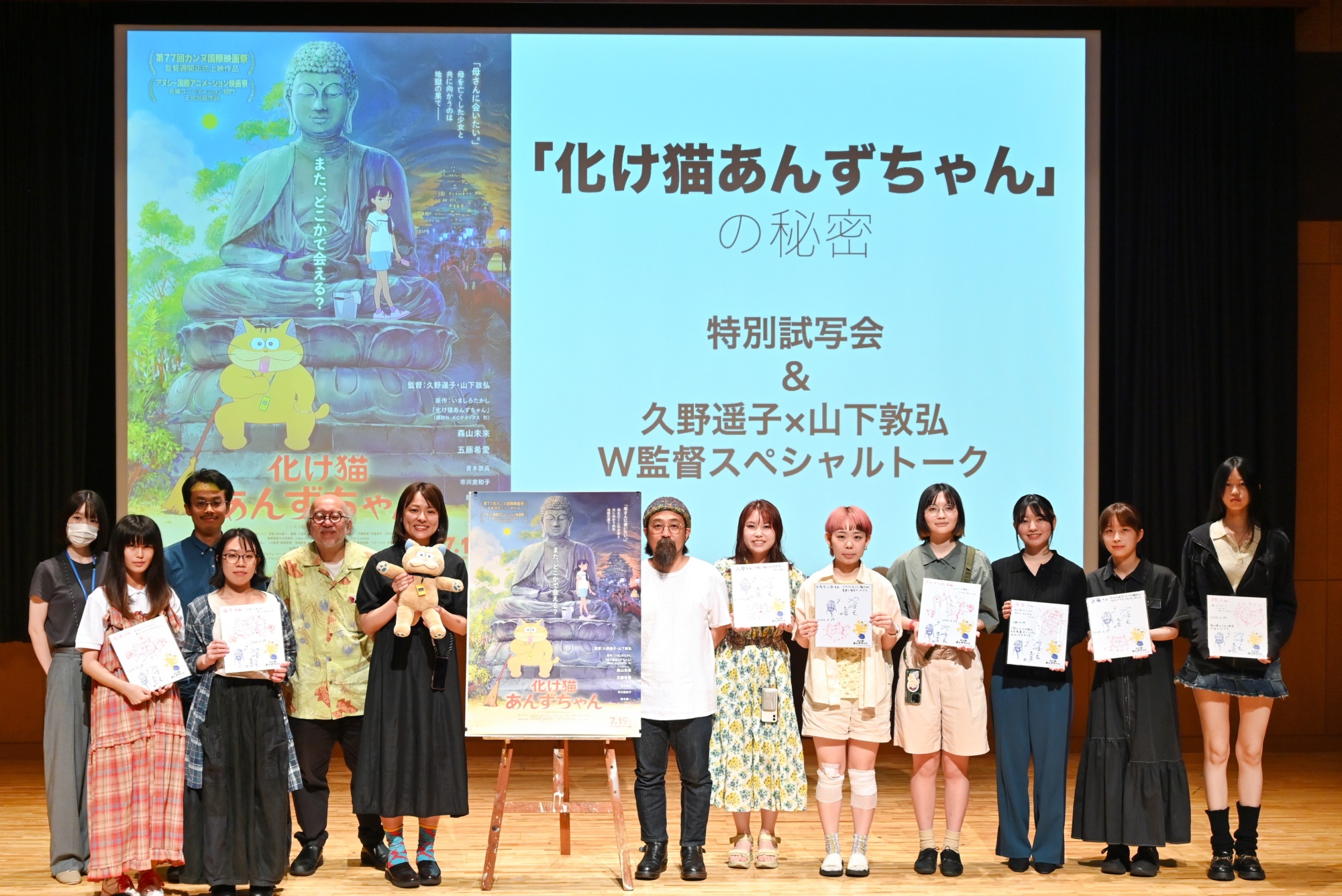 ステージ上に久野監督、山下監督、野村先生と「猫作品」を応募した複数の学生らが賞状を持っている集合写真